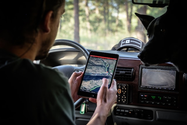 A man in grey shirt sitting in his car and checking a geographic heat map on his iPad.