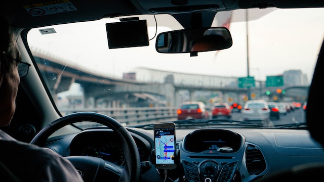 A driver utilizing Google Maps on his mobile phone hands-free while driving.
