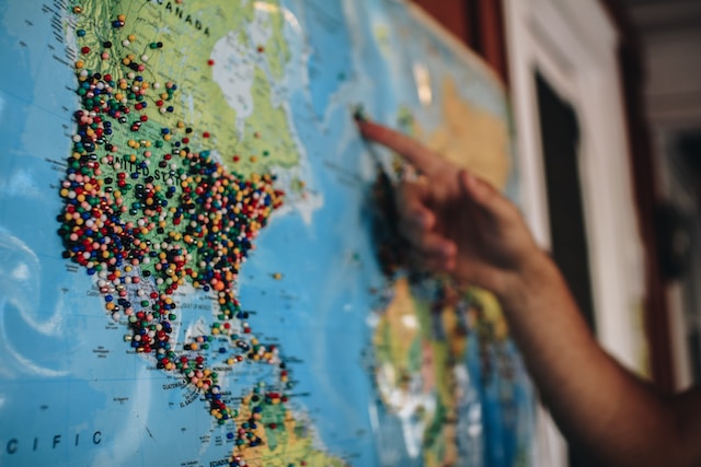 A tourist pointing at a location on a US and Canada map.