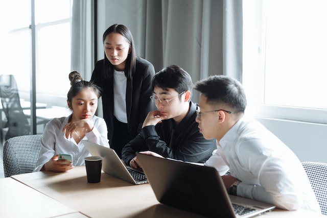 Four members of an organization analyzing company data with Microsoft Excel.