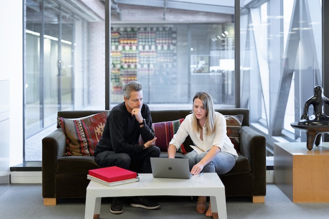 Two real estate agents doing property analysis and market research via a MacBook.