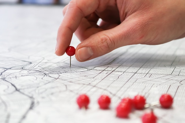 A hand manually optimizing paths via push pins.