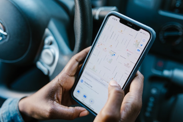A user in his car checking a navigation app on his smartphone before starting his commute.