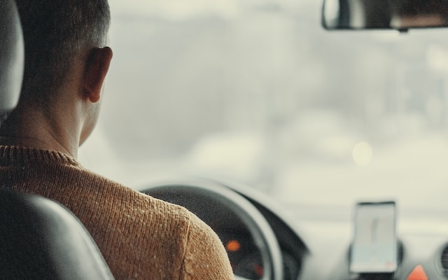 A man in his car using Google Maps to navigate to work.