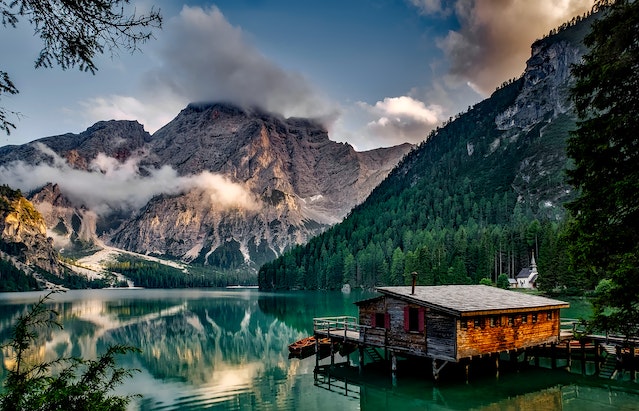 A vacation spot in the middle of a lake, surrounded by mountains and green vegetation.