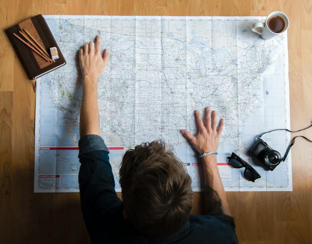 A man studying a particular city on a US physical map.